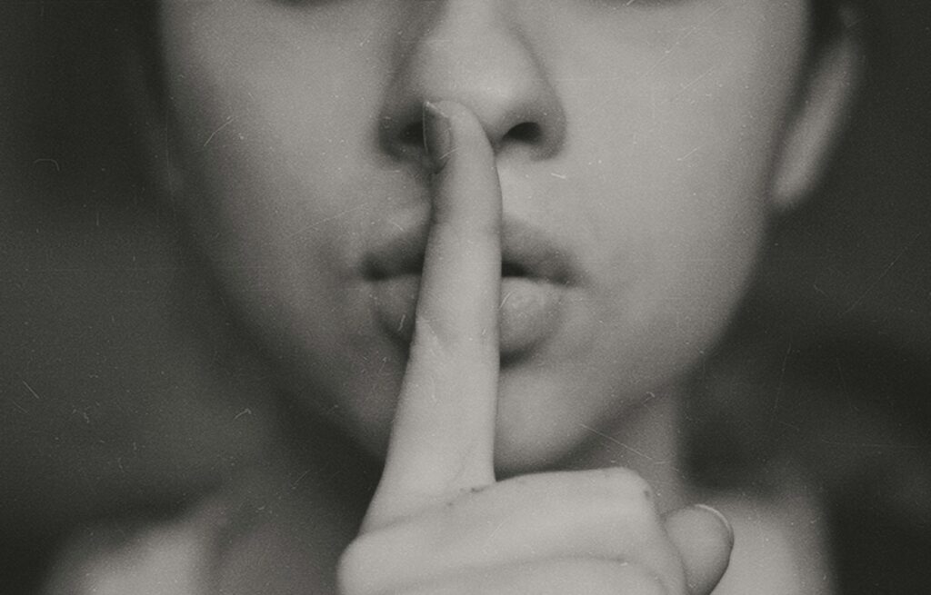 Black and white photo showing a person holding their finger to their lips