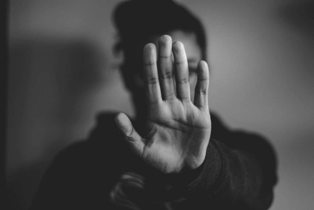 Black and white photo of woman holding up her hand in front of her face